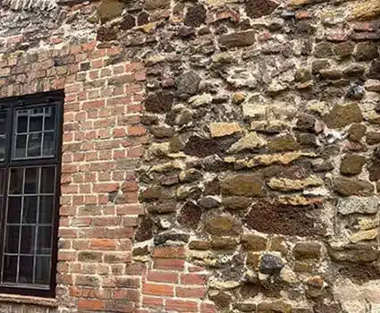 Restored stone and brick wall of a listed building, showcasing historical architecture and preservation techniques relevant to restoration services.