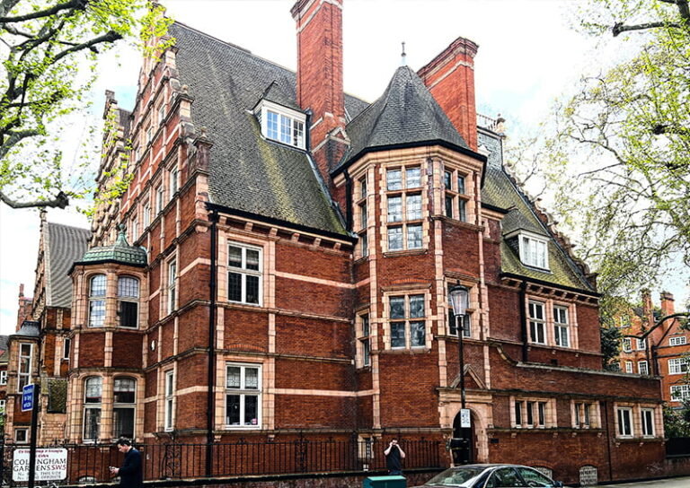 Victorian-style brick building in London, showcasing intricate architecture, large windows, and a steeply pitched roof, relevant to damp survey services.