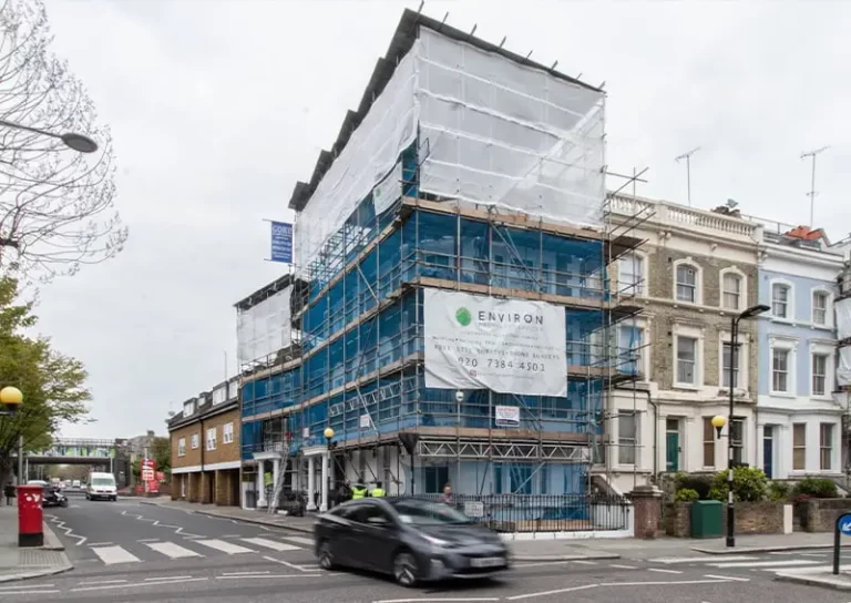 Building under renovation with scaffolding and Environ Restoration Services signage, situated on a London street, highlighting property maintenance and restoration services.