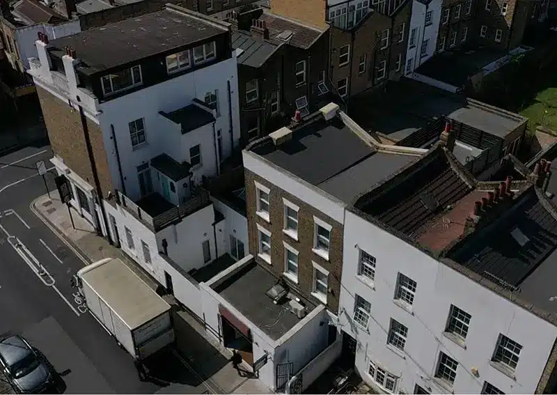 Aerial view of London rooftops showcasing residential and commercial buildings, highlighting the need for drone roof inspections to assess conditions efficiently.