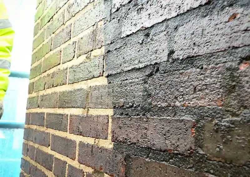 Close-up of a brick wall showing contrasting clean and dirty sections, illustrating the effects of pressure washing for restoration.