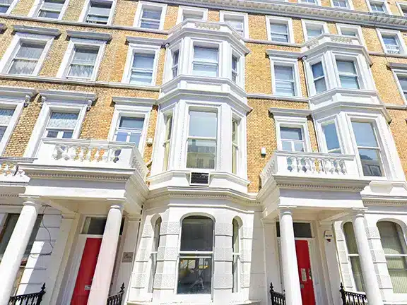 Victorian-style building facade featuring ornate architectural details, large windows, and red doors, relevant to stone wall restoration services by Environ Restoration.
