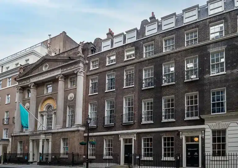 Historic London buildings showcasing architectural details, featuring a prominent entrance with columns and a flag, illustrating the urban landscape relevant to driveway cleaning services.