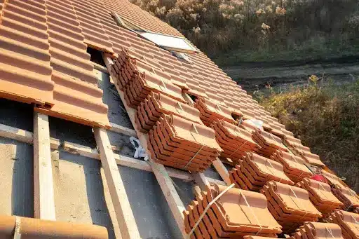Roof under repair with stacked terracotta tiles, showcasing traditional roofing techniques for period properties, highlighting the importance of proper materials in historic building restoration.