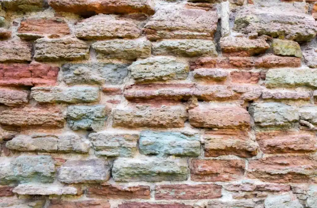 Textured brick wall with varying colours and mortar joints, illustrating the importance of proper repointing techniques for structural integrity and historical preservation.