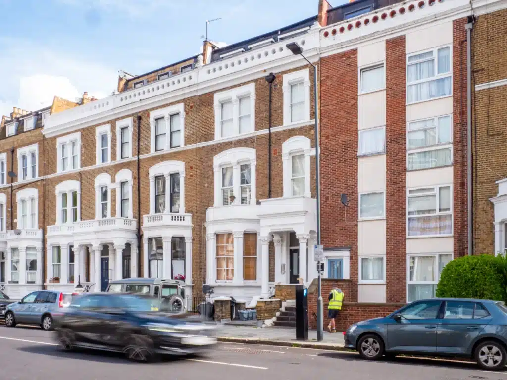 Georgian house facade in London showcasing architectural details, including sash windows and decorative elements, with a restoration worker in a high-visibility vest, highlighting Environ Restoration Services' expertise in historic property restoration.