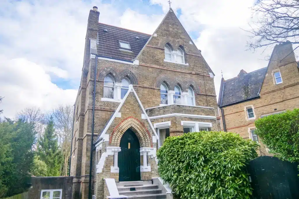 Victorian house exterior showcasing intricate architectural details, including arched windows and a decorative entrance, surrounded by greenery, representing Environ Restoration Services' expertise in preserving historic charm.
