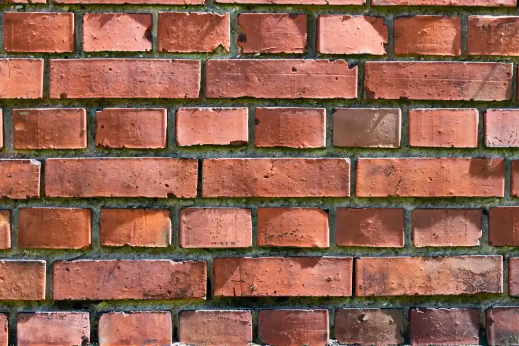 Brick wall with varying shades of red, showcasing texture and potential graffiti removal techniques relevant to brick cleaning and restoration services.