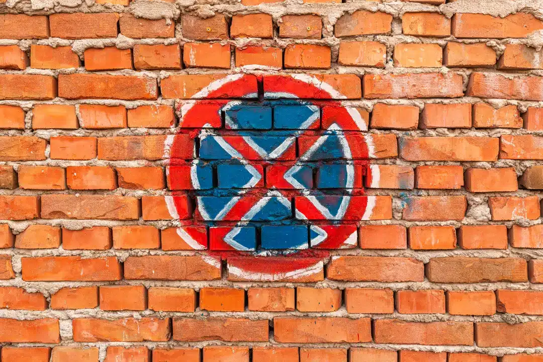 Graffiti symbol painted on a brick wall, showcasing vibrant blue and red colors, representing challenges in graffiti removal and restoration for brick surfaces.
