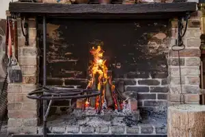 Brick fireplace with burning logs and flames, showcasing the warmth and aesthetic of a clean, well-maintained hearth.