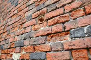 Close-up of weathered brick wall showcasing various shades of red and grey bricks, relevant to brick cleaning and restoration discussions.