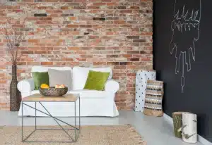Interior space featuring a white sofa with green and grey cushions, a wooden coffee table, and a backdrop of exposed brick walls, illustrating modern brickwork aesthetics and interior design.