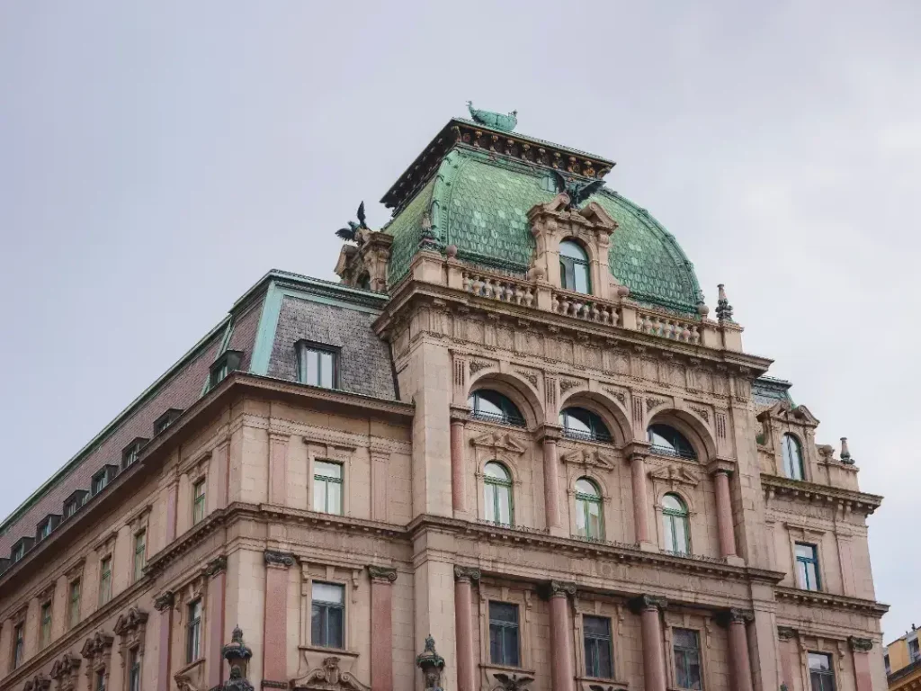 Historic building with ornate architecture, featuring a green domed roof and intricate stone detailing, exemplifying principles of historic conservation and restoration.