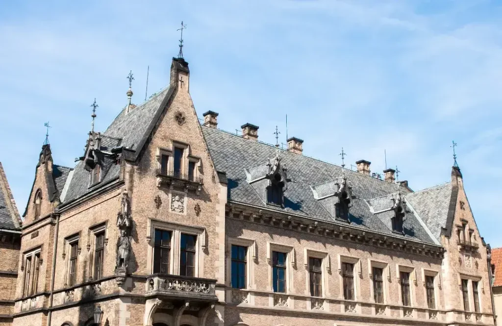 Historic building with intricate architectural details, including decorative stonework, statues, and a steeply pitched roof, exemplifying principles of heritage conservation and authenticity in restoration practices.